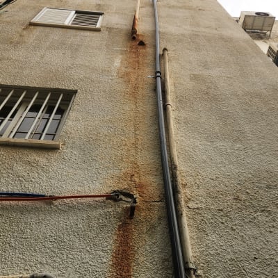 צינורות חיצוניים על קיר בניין עם חלודה