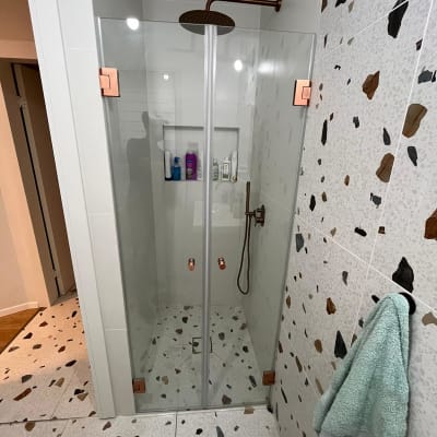 מקלחת עם ראש גשם, בקבוקי שמפו וסבון על מדף