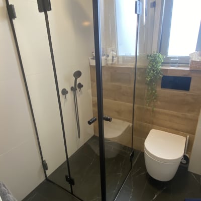 מקלחון זכוכית עם ברזים ושירותים בחדר אמבטיה מודרני