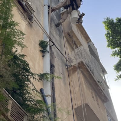 אדם עם ציוד טיפוס עובד על קיר בניין