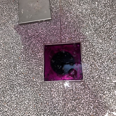 ניקוז עם נוזל צבעוני על רצפה מרוצפת