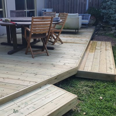 דק עץ עם שולחן וכיסאות בגינה