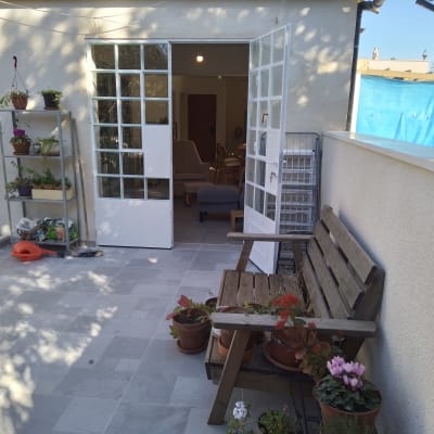 מרפסת עם צמחים, ספסל ודלת זכוכית פתוחה