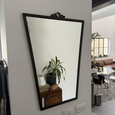 מראה תלויה על קיר עם צמח ברקע