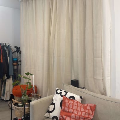 סלון עם ספה, כריות, וילון וכלי עבודה על שולחן