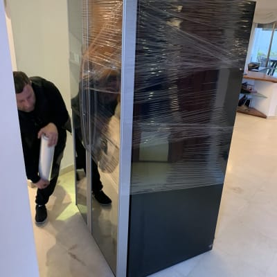 אדם עוטף מקרר בניילון נצמד למעבר דירה