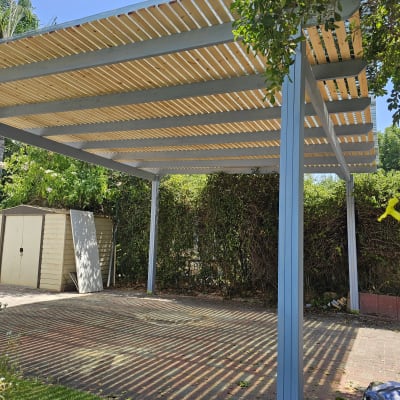 פרגולה מעץ בגינה עם צללים על הקרקע