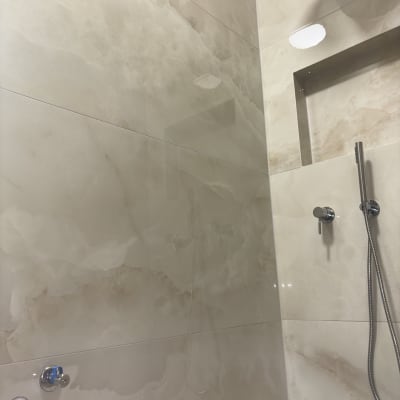 מקלחת נקייה עם אריחים מבריקים וראש מקלחת כסוף