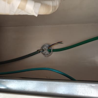 חוטי חשמל צבעוניים יוצאים מצינור ירוק בקיר