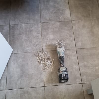 כלי עבודה חשמלי על רצפת אריחים עם שאריות חיתוך