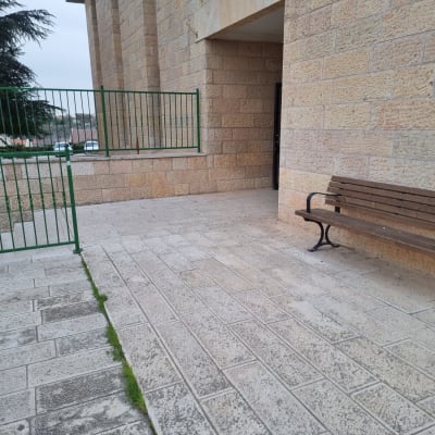 ספסל עץ ליד קיר אבן וגדר ירוקה