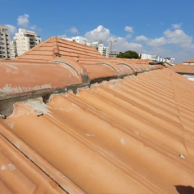 רעפים כתומים על גג עם תיקוני בטון