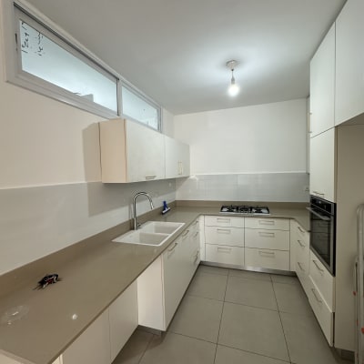 מטבח חדש עם ארונות לבנים ומשטח עבודה בהיר