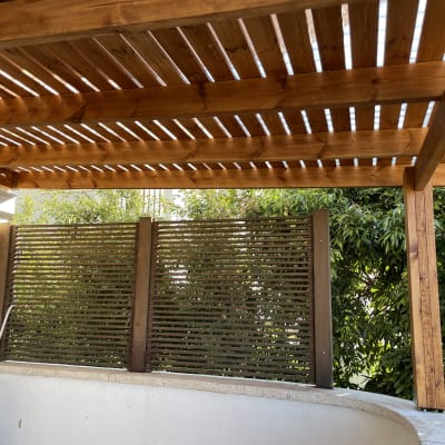 פרגולה מעץ עם גדר עץ וגינה ירוקה