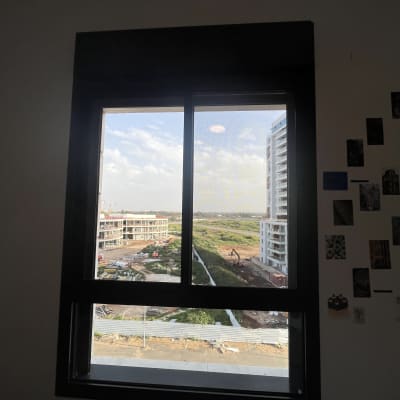 נוף עירוני מבעד לחלון עם בניינים ועבודות בנייה