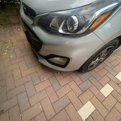 חזית רכב עם פנס קדמי על שביל מרוצף