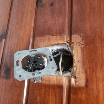 שקע חשמלי פתוח עם חוטים חשופים בקיר עץ