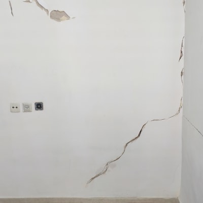 קיר עם סדקים ונזק לצבע על הרצפה