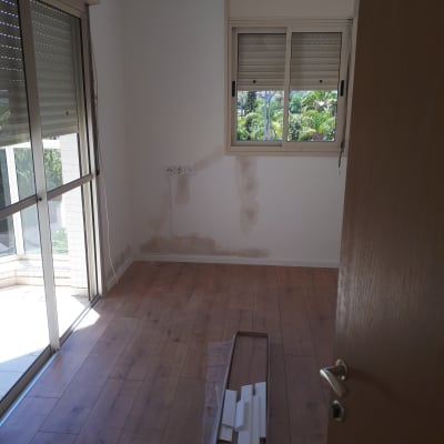 קיר עם תיקוני צבע וחלקי עץ על הרצפה