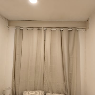 וילון תלוי על מוט בחדר עם קירות לבנים