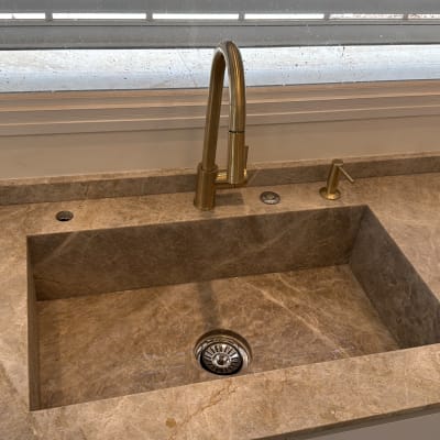 כיור מטבח עם ברז מוזהב ובקבוק חומר ניקוי