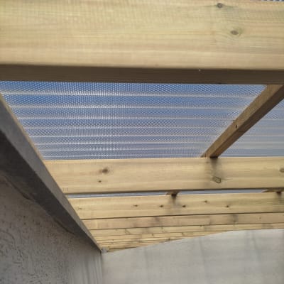 קורות עץ עם כיסוי פלסטיק שקוף בגינה