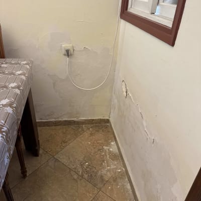 קיר עם קילופי צבע ליד חלון ושולחן