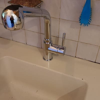 ברז מטבח כסוף עם כיור לבן ומברשת כחולה