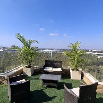 מרפסת עם דשא סינתטי וצמחי נוי בעציצים