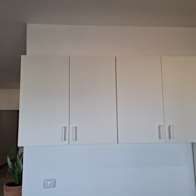 ארון קיר לבן עם דלתות סגורות, אדם מחזיק כלי עבודה