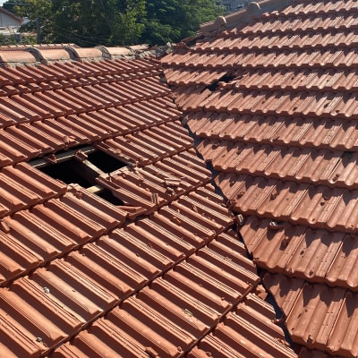 רעפים אדומים על גג עם חור ותיקונים