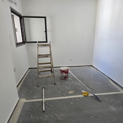 סולם, דלי צבע, מברשת ויריעת כיסוי בחדר צבוע