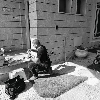 חשמלאי עובד על חוטים ליד קיר חיצוני