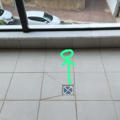 רצפת אריחים עם חץ ירוק מצביע על ניקוז