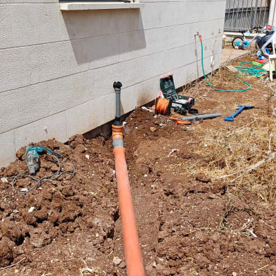 צינור כתום וכלי עבודה ליד קיר חיצוני של בניין