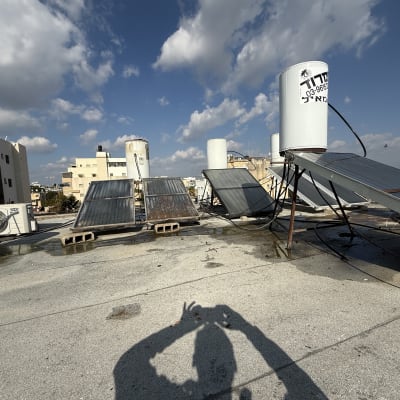 דודי שמש וקולטים על גג תחת שמיים כחולים