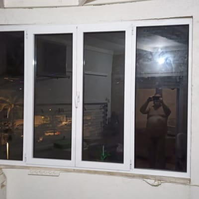 חלון אלומיניום לבן בעל ארבע זגוגיות מותקן בקיר