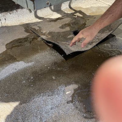 יד בודקת איטום על גג עם יריעות רטובות