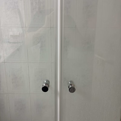 דלתות זכוכית עם ידיות מתכת בחדר אמבטיה
