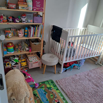 חדר ילדים עם מדף צעצועים, עריסה ושטיח צבעוני