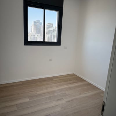 חדר עם רצפת פרקט וחלון עם נוף עירוני