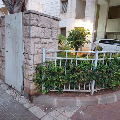 גדר מתכת לבנה עם צמחייה ירוקה מסביב