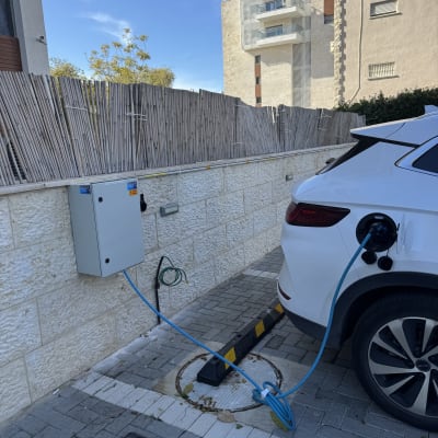 עמדת טעינה לרכב חשמלי מחוברת לרכב לבן