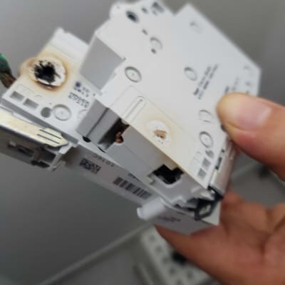 חלק חשמלי עם סימני שריפה מוחזק ביד