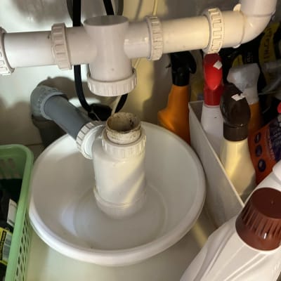 צנרת מתחת לכיור עם חיבורים ומוצרים לניקוי