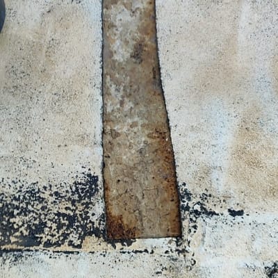 חלק מתכת חלוד מוקף בחומר איטום שחור