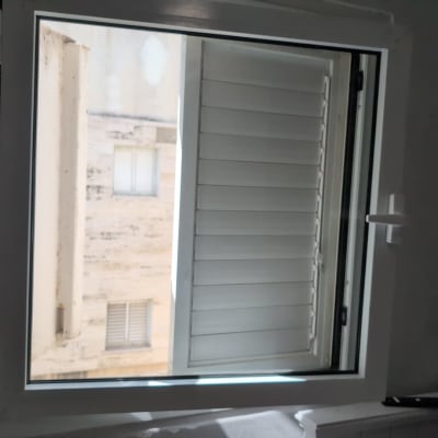 תריסים לבנים פתוחים בחלון פנימי