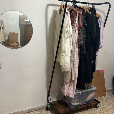 מתלה בגדים עם בגדים תלויים וקופסת אחסון שקופה