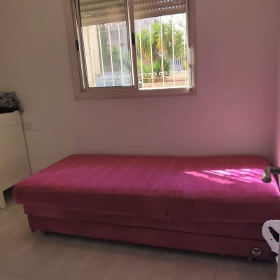 מיטה ורודה בחדר עם חלון פתוח