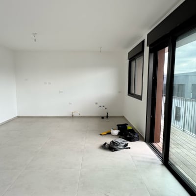 אדם עם כלי עבודה בחדר ריק, תיק וציוד על הרצפה